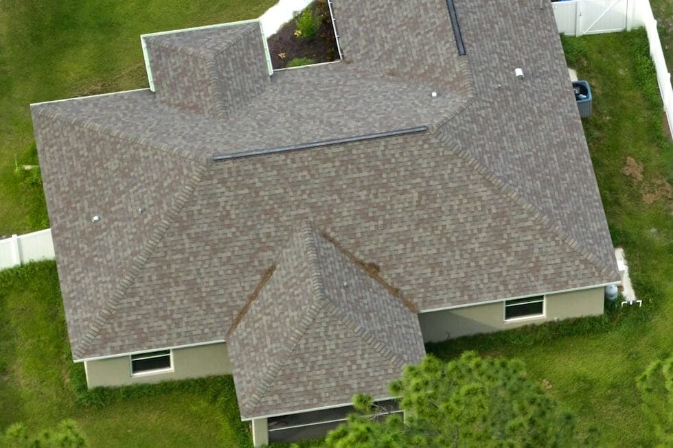 Aerial image of a home with a detailed gray shingle roof, highlighting the intricate patterns and quality workmanship suitable for residential housing.
